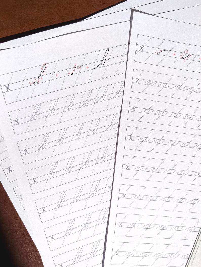 May include: Two white sheets of paper featuring cursive handwriting practice exercises. The left sheet displays rows of the lowercase letter b, while the right sheet shows rows of the lowercase letter a. Each row begins with a grey X.