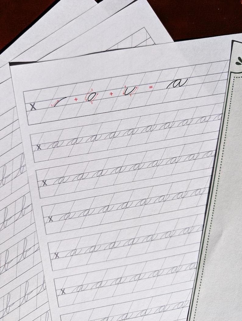 May include: A white practice worksheet for cursive handwriting featuring slanted guide lines. The top row shows the letter a broken down into strokes with the equation X + O + U = a. Below are five rows of the lowercase letter a written in cursive.