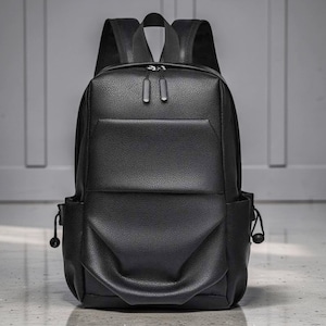Pode incluir: Uma mochila preta com acabamento texturizado e granulado. A bolsa possui um compartimento principal grande com dois puxadores de zíper, um bolso frontal horizontal e dois bolsos laterais com cordões ajustáveis e travas pretas.