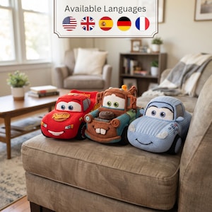 Puede incluir: Tres coches de juguete de ganchillo que representan personajes de la película Cars. El coche rojo tiene un logotipo de Rust-eze, la grúa marrón tiene una parrilla frontal y gancho, y el coche azul claro tiene una cara sonriente y ojos grandes.