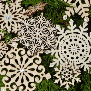 Set von vierzehn verschiedenen Holz Schneeflocken, handdekoriert mit funkelnden Glaskristallen, verschiedenen Größen und Mustern.