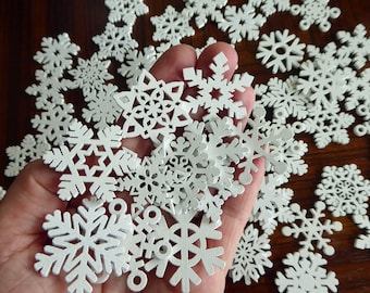 Twenty 35mm, or 1 3/8 inch, white laser cut wood snowflakes