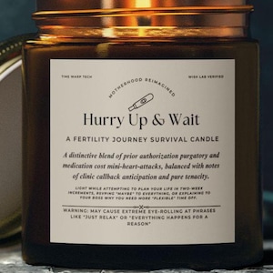 May include: A brown glass candle jar with a white label that reads "Hurry Up & Wait: A Fertility Journey Survival Candle". The label also includes the text "Time Warp Tech", "Motherhood Reimagined", and "Wish Lab Verified".