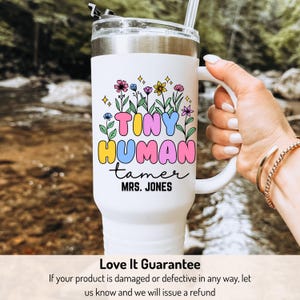 May include: White stainless steel travel mug with a colorful graphic that says "Tiny Human Tamer" and "Mrs. Jones". The graphic features flowers and stars.