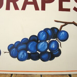 May include: A painted sign featuring a cluster of vibrant blue grapes with a brown stem against a cream-colored background. The word "GRAPES" is displayed in maroon letters at the top. The sign has an orange border.