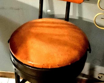オリジナルのオレンジ色のビニール張りの、ビンテージの工業スタイルコンバーチブル製図/バースツール。