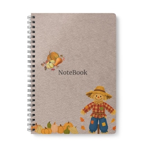 Pode incluir: Um caderno de espiral com uma capa texturizada castanho-clara com a palavra Notebook em cinzento-escuro. O design inclui um grupo de abóboras e um espantalho com camisa aos quadrados e calças azuis, rodeado por folhas de outono espalhadas.