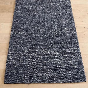May include: A rectangular area rug featuring a thick, textured weave in a blend of dark navy blue and white yarn. The rug has a dense, nubby surface construction with a consistent pattern throughout, creating a deep, multi-tonal appearance.