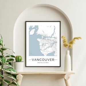 Puede incluir: Una impresión enmarcada en negro de un mapa de Vancouver, Columbia Británica. El mapa está en azul y blanco y muestra las calles y vías fluviales de la ciudad. El texto "Vancouver" y "Columbia Británica" está impreso debajo del mapa.