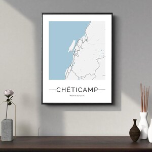 Könnte beinhalten: Ein schwarzer gerahmter Druck einer Karte von Cheticamp, Nova Scotia. Die Karte ist in Schwarzweiß mit hellblauem Hintergrund. Der Text "Cheticamp" und "Nova Scotia" ist in Schwarz unter der Karte gedruckt.