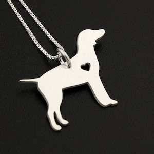 May include: A silver necklace with a pendant shaped like a dog with a heart cut out of its chest. The necklace is on a black background.