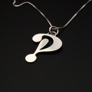 May include: A silver question mark pendant necklace on a silver chain. The pendant is a simple, stylized question mark.