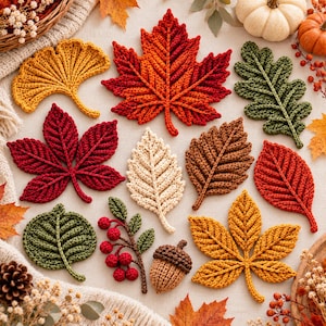 May include: A collection of crocheted autumn leaves and botanical elements including a yellow ginkgo leaf, a red maple leaf, a green oak leaf, a red chestnut leaf, a cream leaf, a brown leaf, a red leaf, a green leaf, red berries, and an acorn.