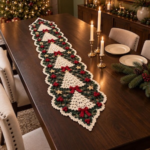 Puede incluir: Un camino de mesa de ganchillo largo y rectangular con un patrón repetitivo de árboles de Navidad de color crema sobre un fondo verde oscuro. El camino está decorado con pequeños lazos rojos, racimos de bayas rojas y estrellas amarillas.
