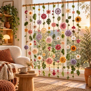 May include: A decorative window hanging featuring multiple vertical strands of crocheted flowers and green leaves in various colors including pink, yellow, purple, and white, suspended from a horizontal wooden rod across a window frame.