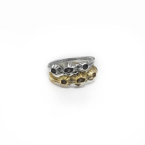 May include: A set of three silver and gold rings with a floral design. The rings are stacked on top of each other.