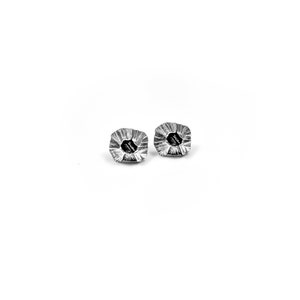 May include: A pair of silver earrings with a textured, organic shape. The earrings have a small hole in the center.