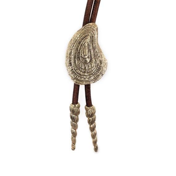 Concho oyster bolo tie with spire shell endcaps, in solid sterling silver or brass, strung with genuine Greek leather cord.
