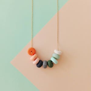 May include: A gold chain necklace with colorful round beads in shades of orange, pink, green, and gray.
