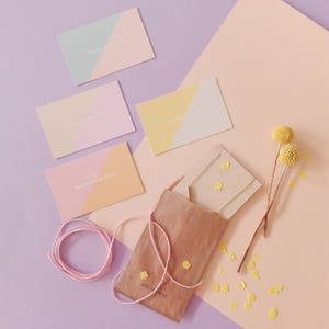 Op de afbeelding: Een bruine papieren envelop met de tekst "honeyandmilk" erop. De envelop is omringd door kleine gele confetti en een paar visitekaartjes met de tekst "honeyandmilk" erop.