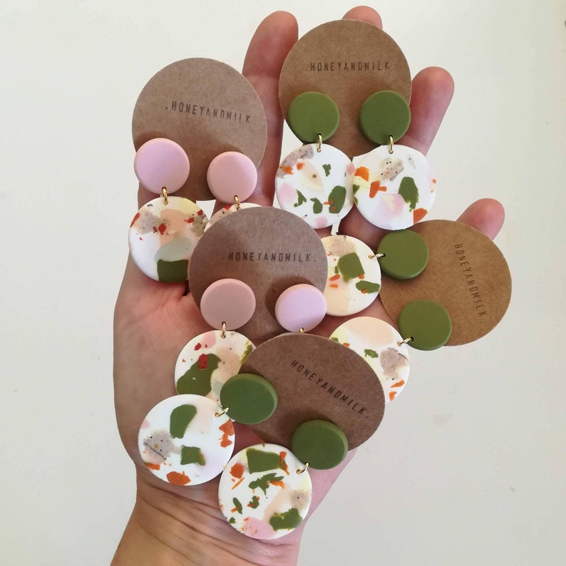 May include: Three pairs of handmade earrings with a white, green, and pink abstract pattern. The earrings are made of polymer clay and have a gold-colored metal post.
