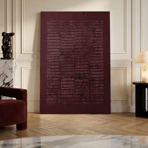 May include: A large rectangular wall art piece in a deep burgundy color featuring a textured surface with horizontal, raised, linear patterns arranged in a grid-like formation across the center, creating a tactile and layered appearance.