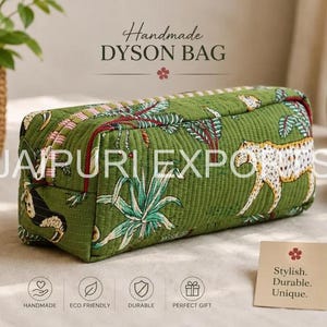 May include: A rectangular quilted bag in a green fabric featuring a printed pattern of cheetahs and tropical plants. The bag has a zippered closure with a striped trim and a red piping detail along the edges. Text on the bag reads HANDMADE DYSON BAG.