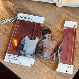 May include: A clear acrylic Instagram-themed keychain set featuring a male figure with dark hair and tattoos on both arms. The design includes a white tank top, a shirtless torso, and social media interface elements like the Instagram logo, heart icon, and the text 3, 132, 000次赞.