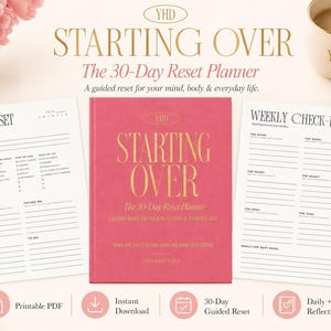 Könnte beinhalten: Ein rosafarbener Planer mit dem Titel Starting Over The 30-Day Reset Planner in goldener Schrift, flankiert von zwei weißen bedruckten Seiten mit der Aufschrift Daily Reset und Weekly Check-In für einen geführten Reset von Geist und Körper.