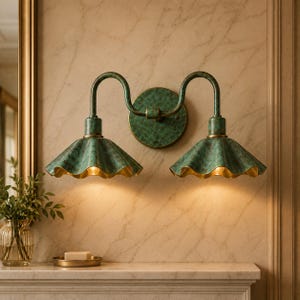 May include: A double wall sconce light fixture featuring a textured, weathered green patina finish. The design includes two curved arms extending from a circular backplate to support two fluted, bell-shaped shades with warm interior lighting.