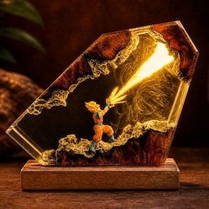 May include: A decorative lamp featuring a miniature figure of a spiky-haired character in an orange gi, positioned within a clear resin block encased by dark wood. The figure emits a bright yellow light beam, creating a glowing effect.