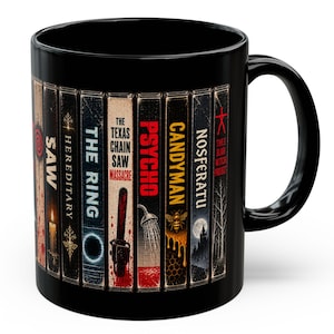 Può includere: Una tazza in ceramica nera con una grafica avvolgente che raffigura i dorsi di videocassette vintage. I titoli includono Saw, Hereditary, The Ring, The Texas Chain Saw Massacre, Psycho, Candyman, Nosferatu e The Blair Witch Project con immagini.