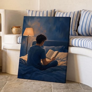 May include: A rectangular canvas print depicting a person sitting on a bed in a dimly lit room, reading an open book. A floor lamp with a warm-toned shade stands beside the bed, casting a soft glow against the deep blue walls and bedding.