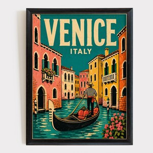 May include: A framed travel poster featuring a gondolier in a striped shirt steering a black gondola through a canal in Venice, Italy. The scene includes colorful buildings in shades of pink and yellow, with the text VENICE ITALY at the top.
