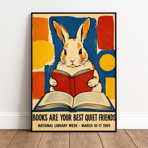 May include: A framed poster featuring a light brown rabbit reading a red book. The background has abstract blue, orange, and yellow shapes. Text reads: BOOKS ARE YOUR BEST QUIET FRIENDS, NATIONAL LIBRARY WEEK - MARCH 10-17 1969. The frame is metallic gold.