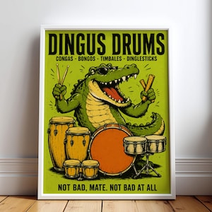 May include: A framed poster featuring a green crocodile wearing sunglasses and playing a drum set. The text reads DINGUS DRUMS CONGAS - BONGOS - TIMBALES - DINGLESTICKS and NOT BAD, MATE. NOT BAD AT ALL. The background is lime green with orange and brown drums.
