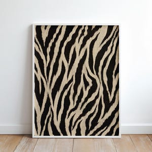 May include: A rectangular wall art print featuring a high-contrast zebra stripe pattern in black and beige. The artwork is encased in a thin white frame, displaying vertical, irregular, and organic lines that mimic the natural animal print design.