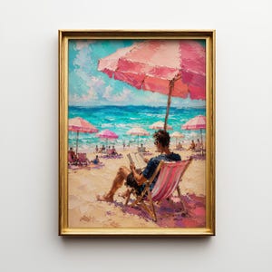 May include: An oil painting in a gold frame depicting a beach scene with a person sitting in a striped beach chair under a large pink umbrella, reading a book. The scene features turquoise ocean water, sandy shores, and multiple pink umbrellas.