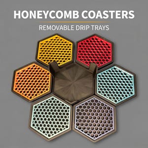 May include: A set of hexagonal honeycomb coasters with removable drip trays, featuring the text HONEYCOMB COASTERS and REMOVABLE DRIP TRAYS. The coasters come in yellow, red, orange, light blue, mint green, and purple with black frames.