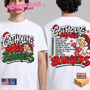 May include: A white t-shirt featuring a graphic of a goose wearing a Santa hat and a red plaid bow. The front text reads CATHOLIC MASS BANGERS. The back displays the same goose graphic with a list of ten song titles and the text CATHOLIC MASS BANGERS.