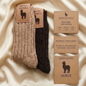 May include: Two pairs of ribbed knit socks in beige and dark gray, labeled Qorux Alpaka. Includes informational cards detailing sizing for small, medium, and large, and a material composition of 40% alpaca, 45% wool, 12% polyamid, and 3% elasthan.