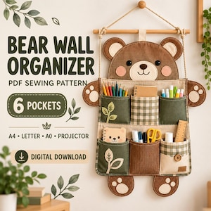 May include: A bear-shaped wall organiser with six pockets, featuring brown, olive green, and beige checkered fabric. The organiser has a bear face at the top, paw-shaped side accents, and hangs from a wooden rod with rope. Text reads: BEAR WALL ORGANISER PDF SEWING PATTERN 6 POCKETS A4 LETTER A0 PROJECTOR DIGITAL DOWNLOAD.
