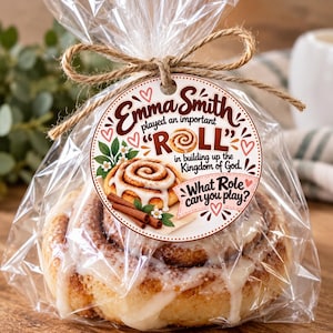 May include: A cinnamon roll with white icing packaged in a clear plastic bag tied with brown twine. A round paper tag is attached, featuring the text: Emma Smith played an important ROLL in building up the Kingdom of God. What Role can you play?