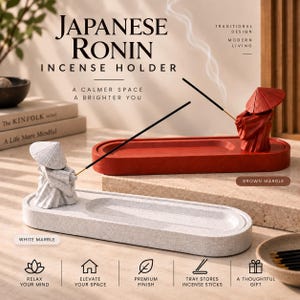 May include: Two oval incense holders featuring a figurine of a person wearing a conical hat and robes. One holder is white marble with a white figurine, and the other is brown marble with a red figurine. Each holds a lit incense stick with smoke.