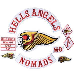 May include: A collection of embroidered patches featuring a large white arched patch with red text reading HELLS ANGELS, a central winged skull emblem, a white arched patch with red text reading NOMADS, two diamond patches with 1% text, and MC text.