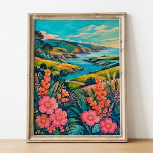 May include: A framed landscape painting featuring a vibrant coastal scene with rolling green hills, a blue river flowing toward the sea, and a bright sky. The foreground is filled with detailed pink and orange flowers and green foliage.