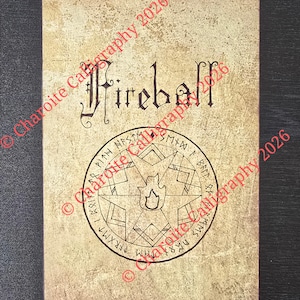 May include: A rectangular wall scroll with a beige, textured background featuring the word Fireball in black calligraphy at the top. Below the text is a circular emblem containing a star, a flame icon, and runic characters. The scroll has light wood rods at the top and bottom.