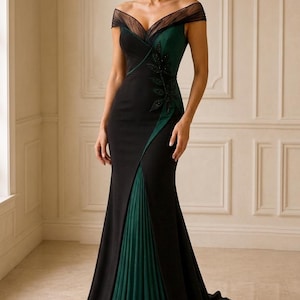 May include: A floor-length black and dark green gown featuring an off-the-shoulder neckline with sheer black mesh detailing, a fitted bodice with a dark green side panel adorned with leaf-shaped embellishments, and a pleated green skirt insert.