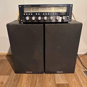 May include: A black Marantz Model 2265B stereophonic receiver with a silver control panel, analogue tuning display, and two illuminated meters, positioned atop two large, rectangular black speakers with fabric grilles.