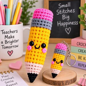May include: Two crochet pencil-shaped items with smiling faces, pink cheeks, and black eyes. The larger pencil has a pink eraser, gray ferrule, yellow body, and black tip. The smaller pencil is a keychain with identical features and colors.